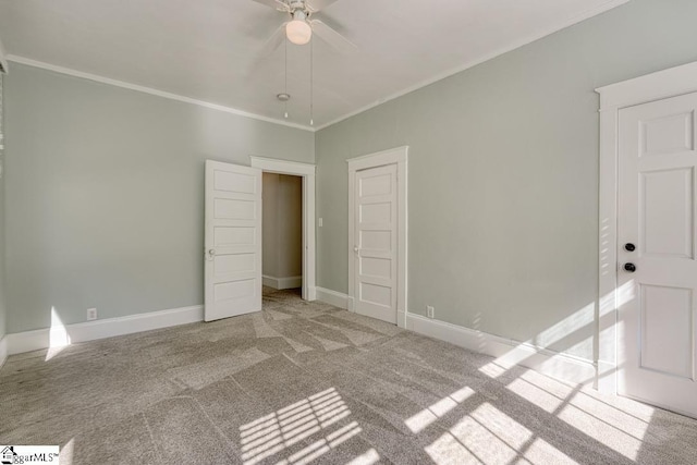 unfurnished bedroom featuring crown molding, carpet floors, baseboards, and a ceiling fan
