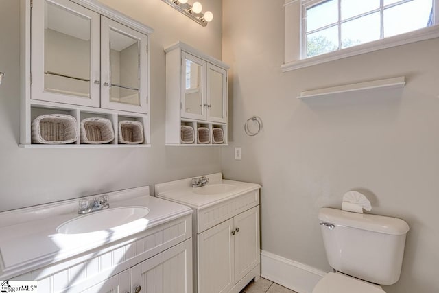 bathroom featuring toilet, two vanities, a sink, and tile patterned flooring