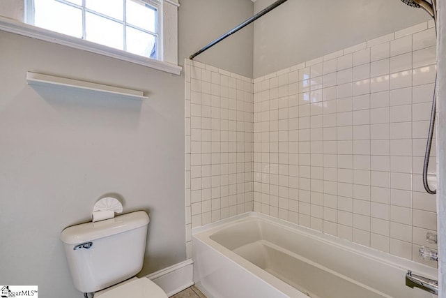 bathroom with washtub / shower combination, baseboards, and toilet