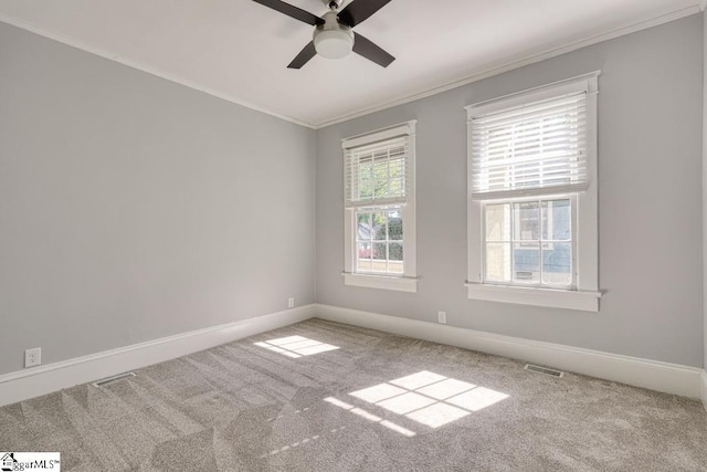carpeted empty room with visible vents, ornamental molding, baseboards, and ceiling fan