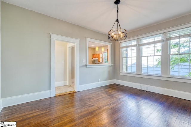unfurnished dining area with dark wood-style flooring, an inviting chandelier, and a healthy amount of sunlight