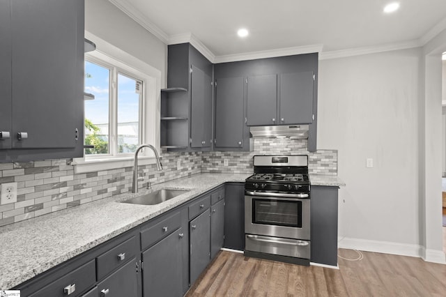 kitchen featuring decorative backsplash, a sink, stainless steel gas range, under cabinet range hood, and light wood-style flooring