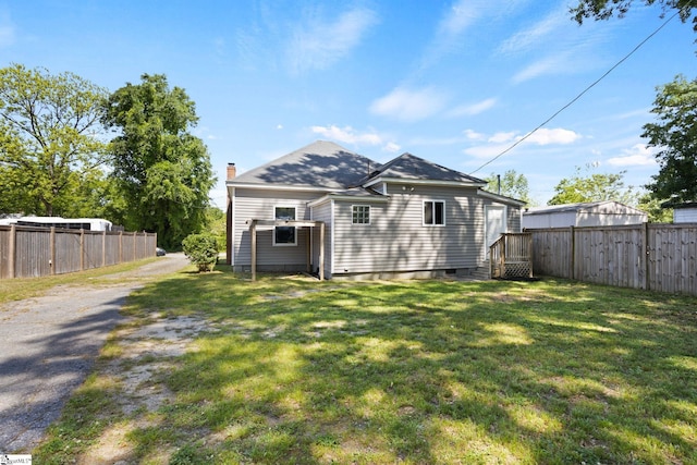 rear view of house with a yard, fence, and a chimney