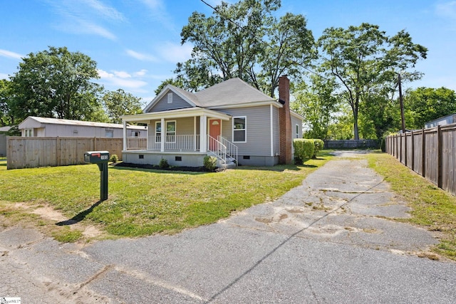 bungalow-style home featuring a front lawn, a chimney, crawl space, a porch, and driveway