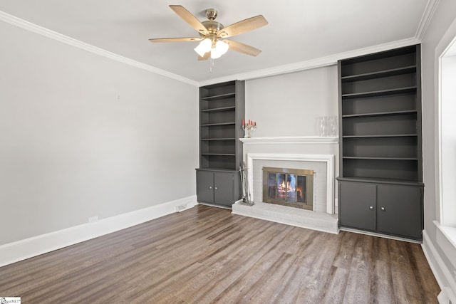 unfurnished living room featuring a fireplace, a ceiling fan, baseboards, wood finished floors, and ornamental molding