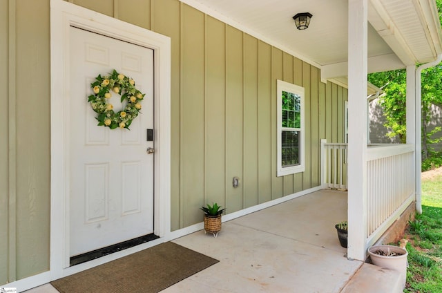 view of exterior entry with a porch and board and batten siding