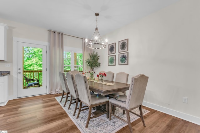 dining area with an inviting chandelier, baseboards, and light wood-type flooring