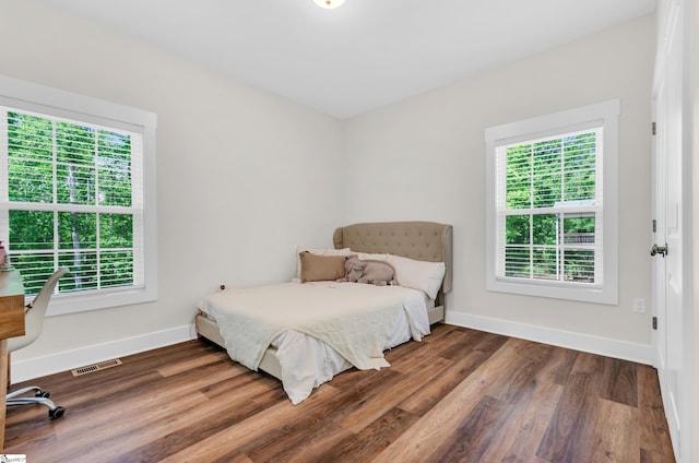 bedroom featuring baseboards, wood finished floors, and multiple windows