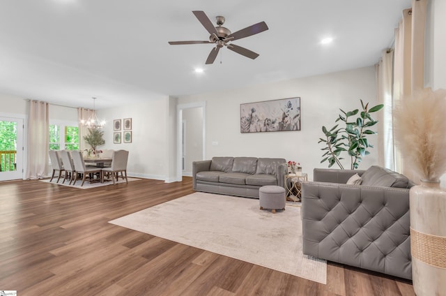 living area with recessed lighting, baseboards, wood finished floors, and ceiling fan with notable chandelier