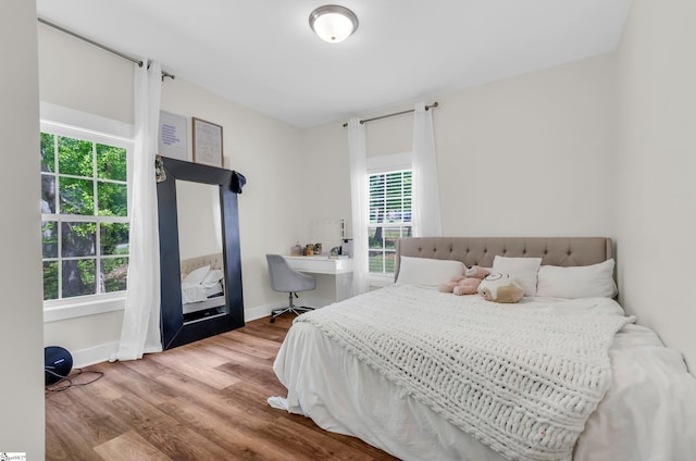 bedroom with baseboards, multiple windows, and wood finished floors