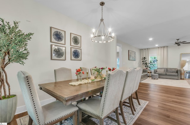 dining space featuring wood finished floors and ceiling fan with notable chandelier