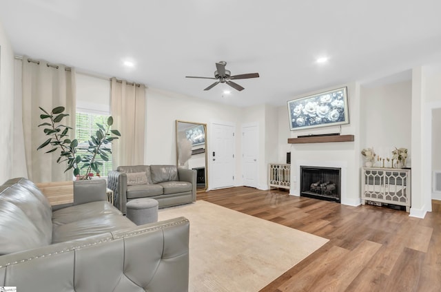living area with ceiling fan, a fireplace, recessed lighting, baseboards, and wood finished floors