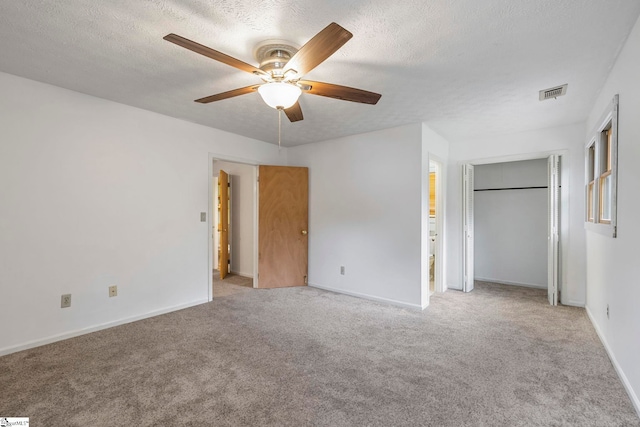 unfurnished bedroom featuring visible vents, a textured ceiling, baseboards, and light carpet