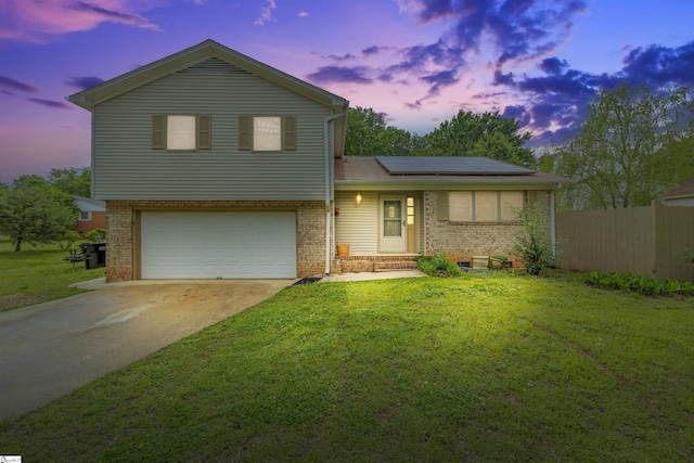 split level home with a lawn, solar panels, and brick siding