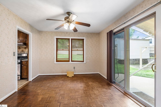 spare room featuring a healthy amount of sunlight, baseboards, and a ceiling fan