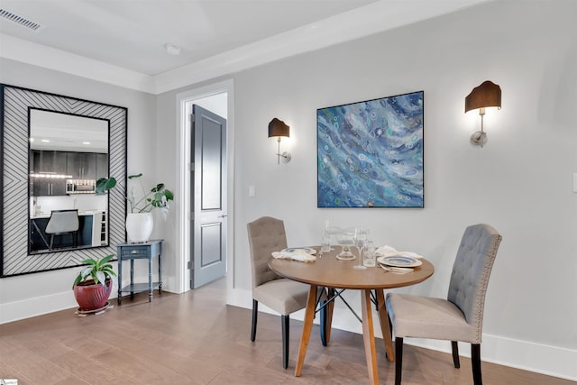 dining room with baseboards, visible vents, and wood finished floors
