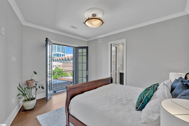 bedroom with access to exterior, baseboards, wood finished floors, visible vents, and ornamental molding