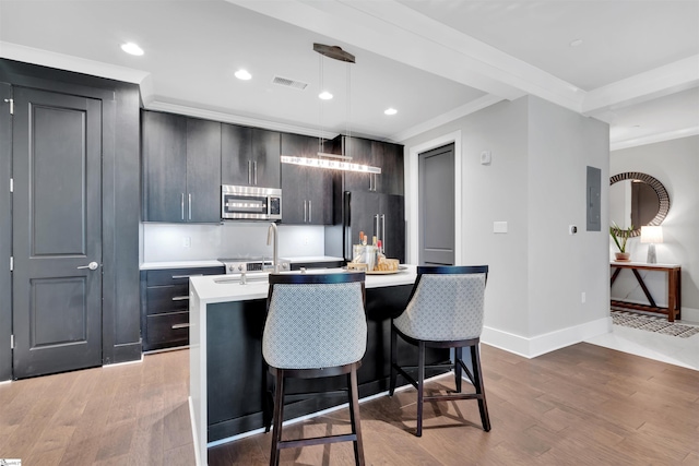 kitchen featuring light countertops, a kitchen island with sink, stainless steel microwave, visible vents, and high quality fridge