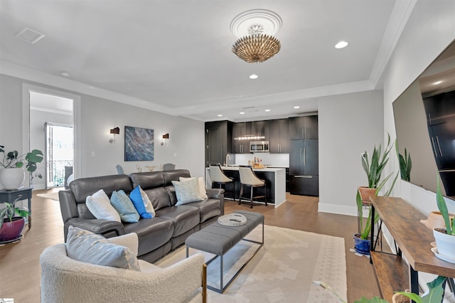 living room featuring crown molding, recessed lighting, baseboards, and light wood-style flooring