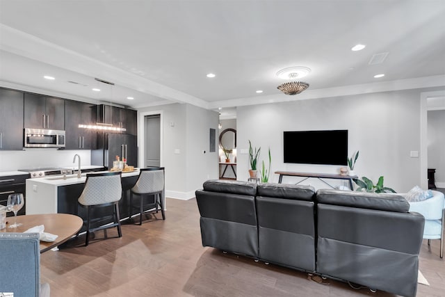 living room featuring visible vents, ornamental molding, baseboards, recessed lighting, and light wood finished floors