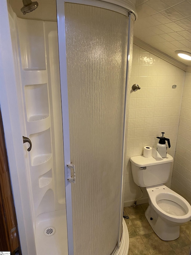 bathroom with tile patterned flooring, a stall shower, toilet, and tile walls