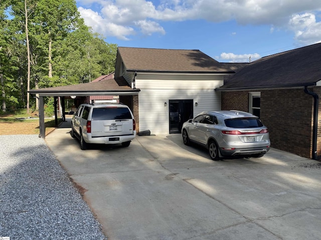 view of home's exterior featuring roof with shingles, driveway, and brick siding