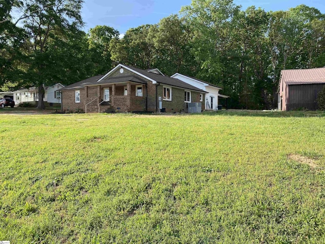 ranch-style home with covered porch, brick siding, central AC unit, and a front lawn