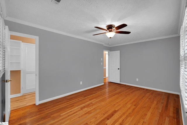 unfurnished bedroom with a textured ceiling, baseboards, ornamental molding, and light wood-style floors