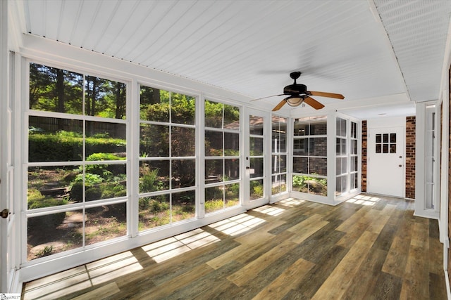 unfurnished sunroom with wood-type flooring, a ceiling fan, a healthy amount of sunlight, and french doors