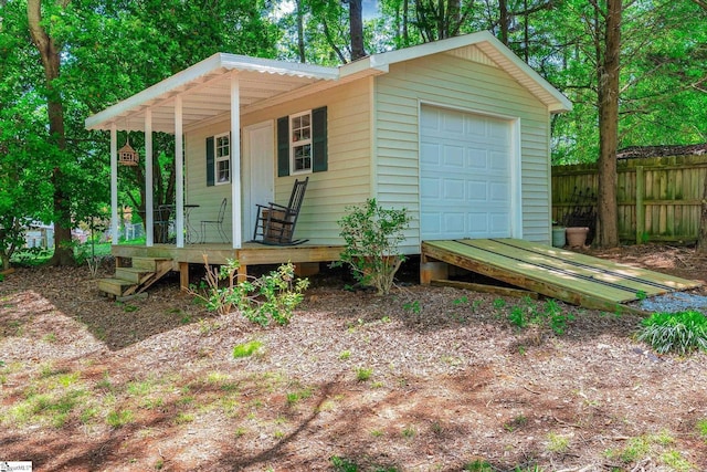 view of outbuilding with fence and covered porch