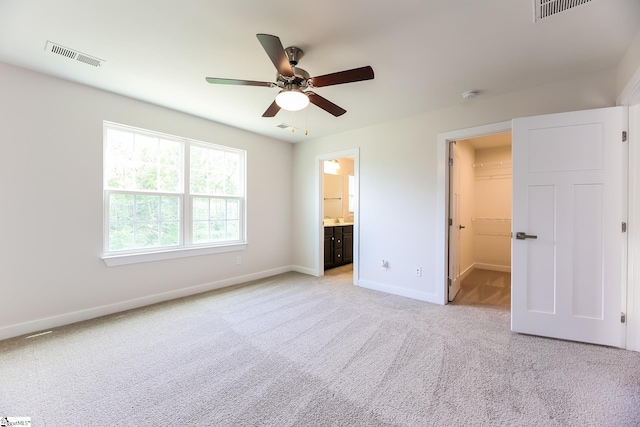 unfurnished bedroom with light colored carpet, baseboards, visible vents, and a spacious closet