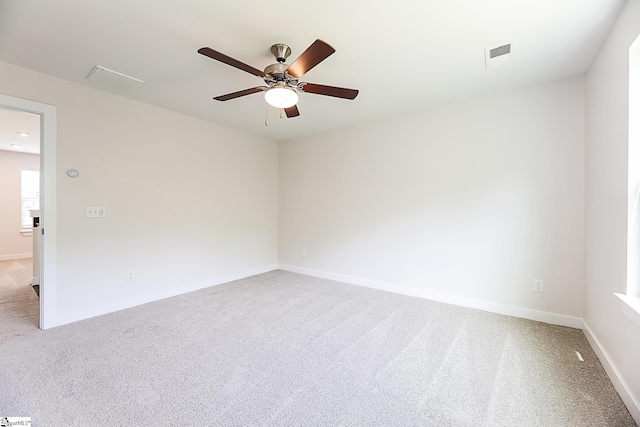 unfurnished room featuring baseboards, ceiling fan, light carpet, and visible vents