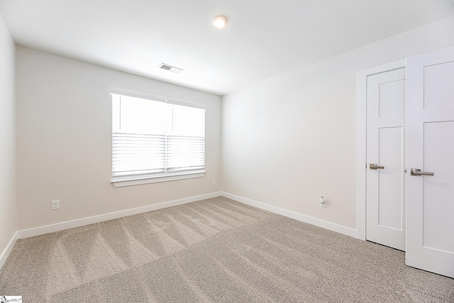 spare room featuring carpet floors, baseboards, and visible vents