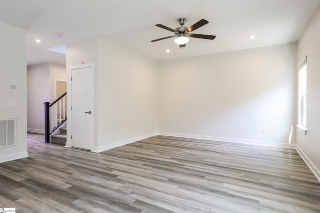 unfurnished room with visible vents, ceiling fan, wood finished floors, and stairway
