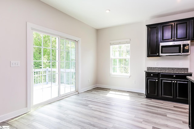 unfurnished dining area with baseboards and light wood finished floors