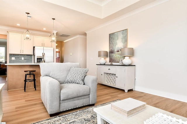 living area featuring crown molding, visible vents, and light wood-type flooring