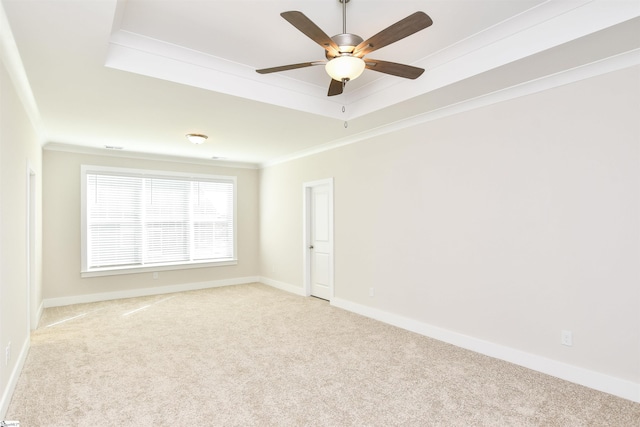 spare room featuring crown molding, baseboards, ceiling fan, and light carpet