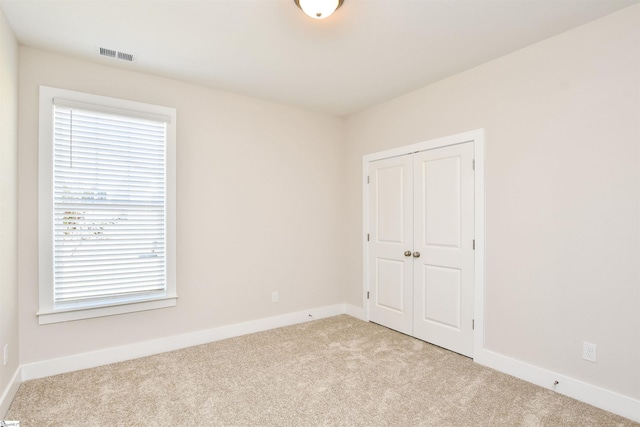empty room featuring light colored carpet, baseboards, and visible vents