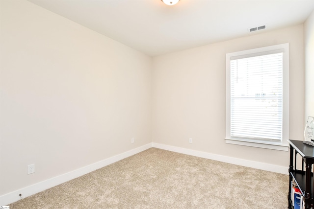 empty room with carpet flooring, baseboards, and visible vents