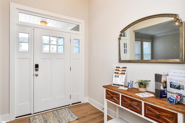 foyer featuring baseboards, arched walkways, crown molding, and wood finished floors