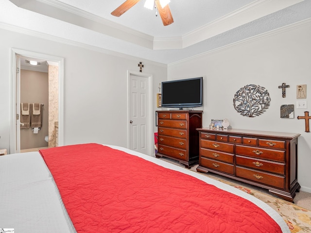 bedroom with crown molding, ensuite bathroom, ceiling fan, light colored carpet, and a raised ceiling