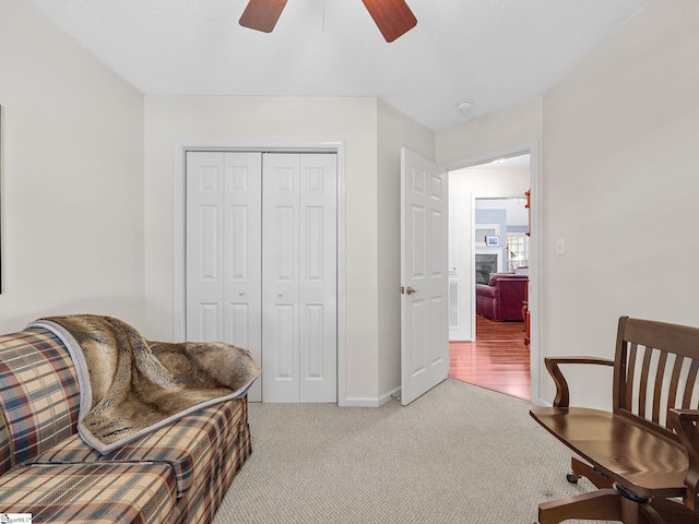 sitting room featuring a ceiling fan, baseboards, and light colored carpet