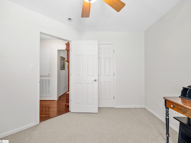 unfurnished office with visible vents, carpet, ceiling fan, and baseboards