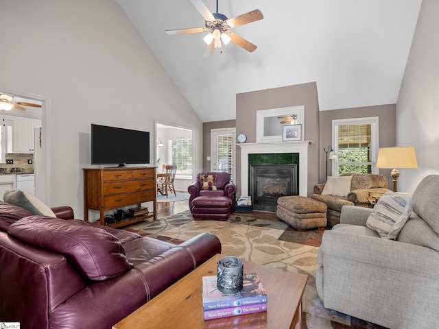living area featuring a glass covered fireplace, high vaulted ceiling, and a ceiling fan