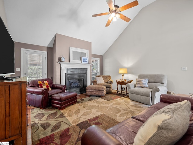 living area featuring a glass covered fireplace, ceiling fan, and high vaulted ceiling