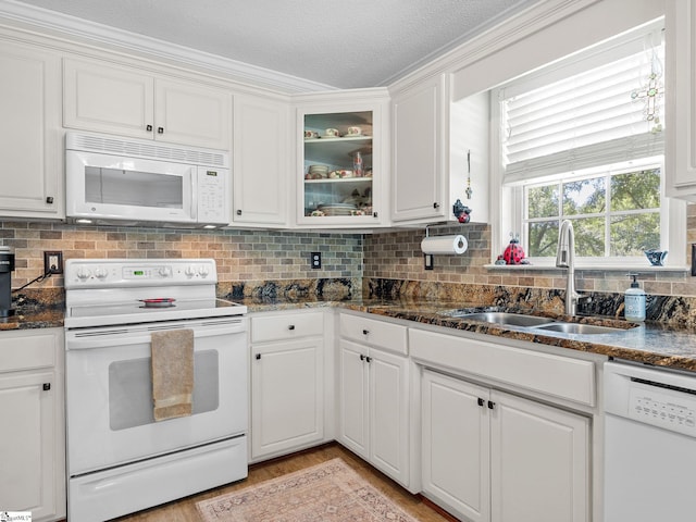 kitchen featuring a sink, white cabinets, backsplash, and white appliances