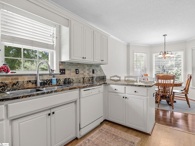 kitchen with a notable chandelier, a sink, dishwasher, a textured ceiling, and a wealth of natural light