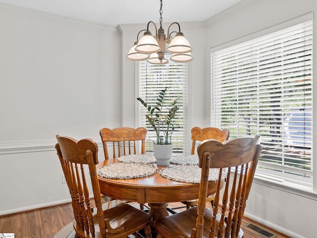 dining area featuring baseboards, wood finished floors, a chandelier, and visible vents