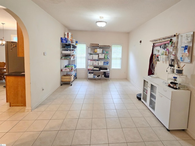 interior space featuring arched walkways, baseboards, and light tile patterned flooring