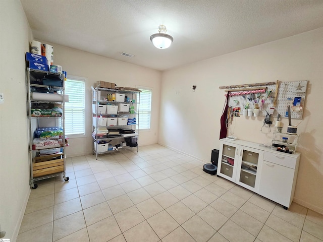 interior space with light tile patterned floors, baseboards, a textured ceiling, and visible vents